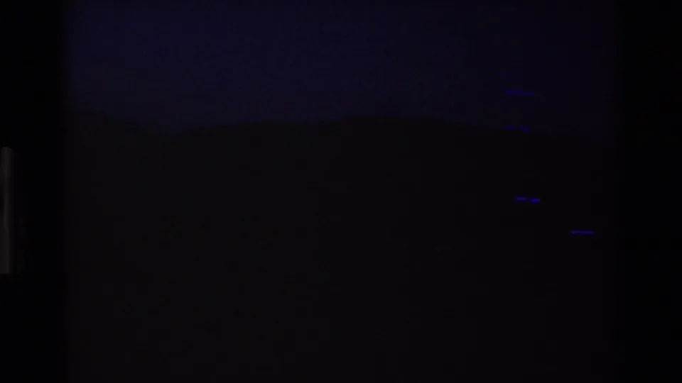 Nearly black 8mm end segment with visible grain, faint blue streaks, and no identifiable people or objects.