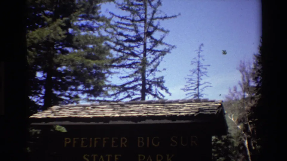 Pfeiffer Big Sur State Park sign remains centered, with the roof, trees, and bright sky visible in the 1980 home-movie frame.