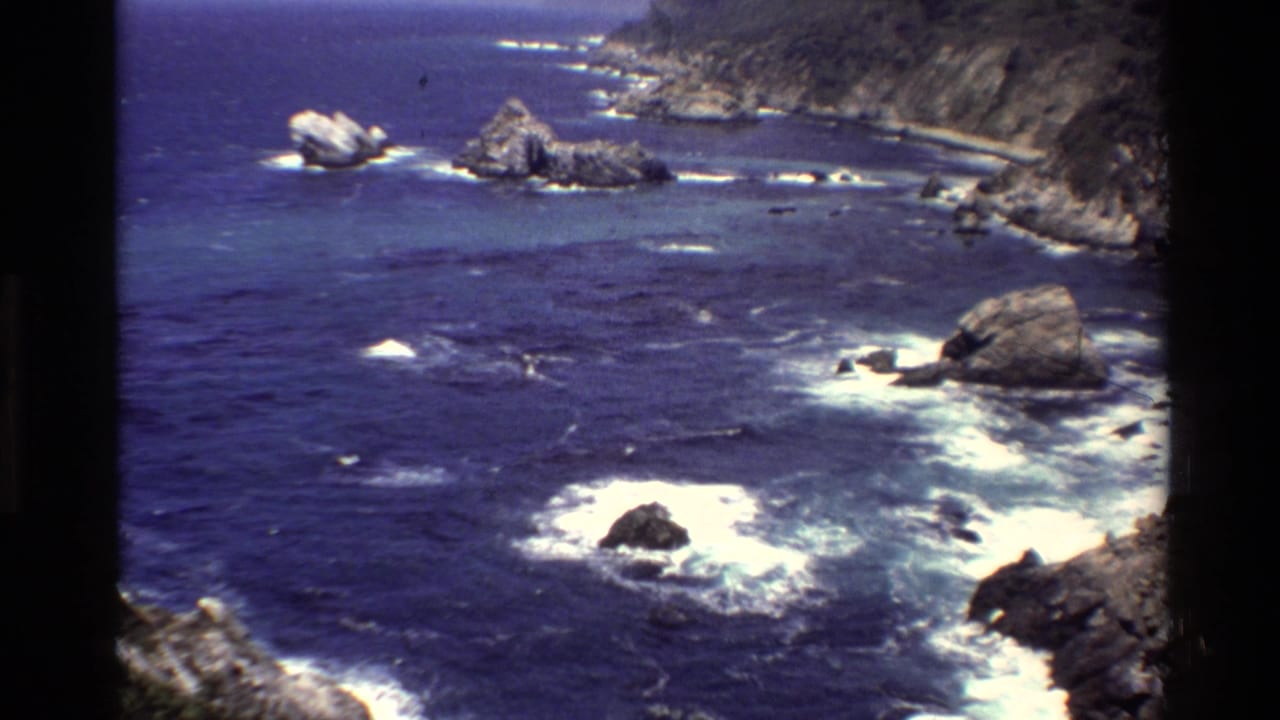 Rocky Pacific shoreline with whitecaps around offshore formations.