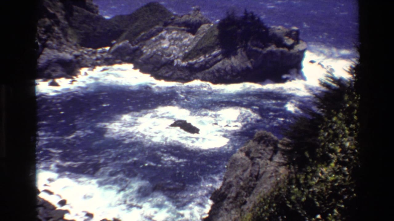 Rocky coastline with white surf breaking below steep cliffs.