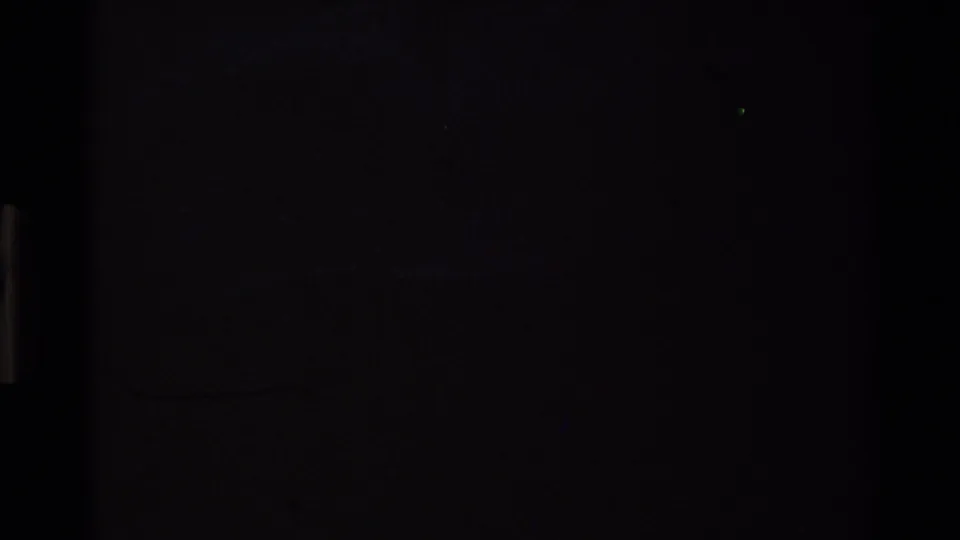 Near-black frame from a 1980s Super 8 reel of the California coast — faint hill silhouette barely visible as the film fades to dark at reel end.