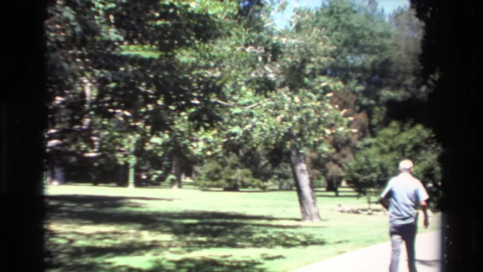 Older man in a light blue shirt walks away along a sunlit path in a green Big Sur park setting, based on clip metadata.