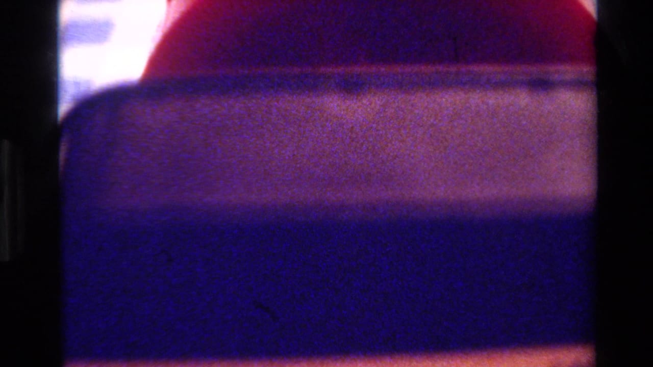 Close-up of a rounded red object beside a dark blue-purple band and pale background.