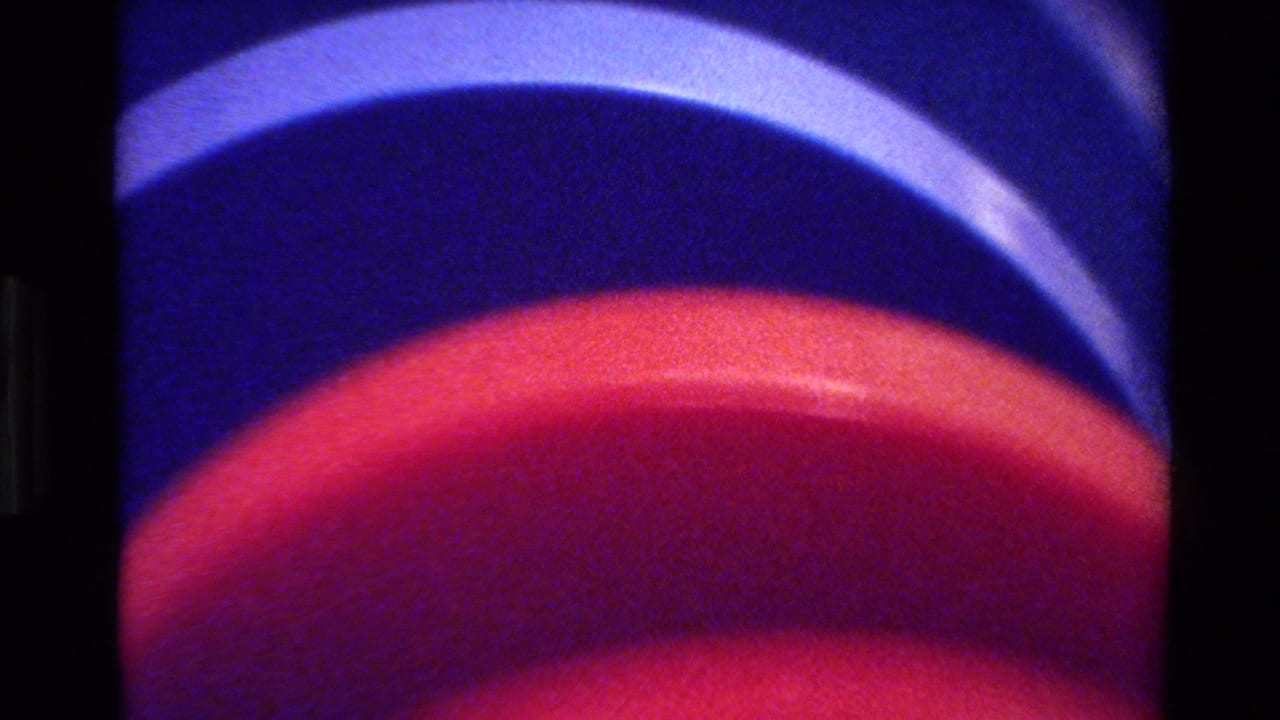 1980 Big Sur 8mm frame of stacked round red and blue forms, seen close up with soft grain and black gate edges.