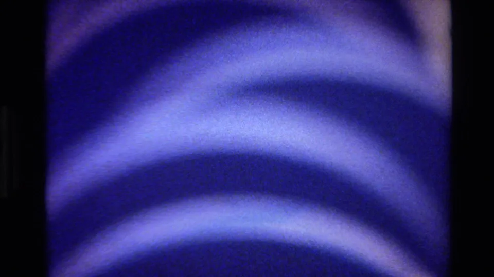 Final 8mm frame from the 1980 Big Sur clip, showing soft repeated blue arcs on a rounded surface.