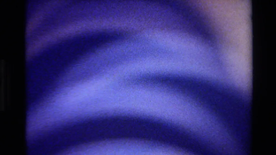 Soft blue wave-like texture in a 1980 Big Sur 8mm frame, with analog grain, diffuse highlights, and a pale edge at right.