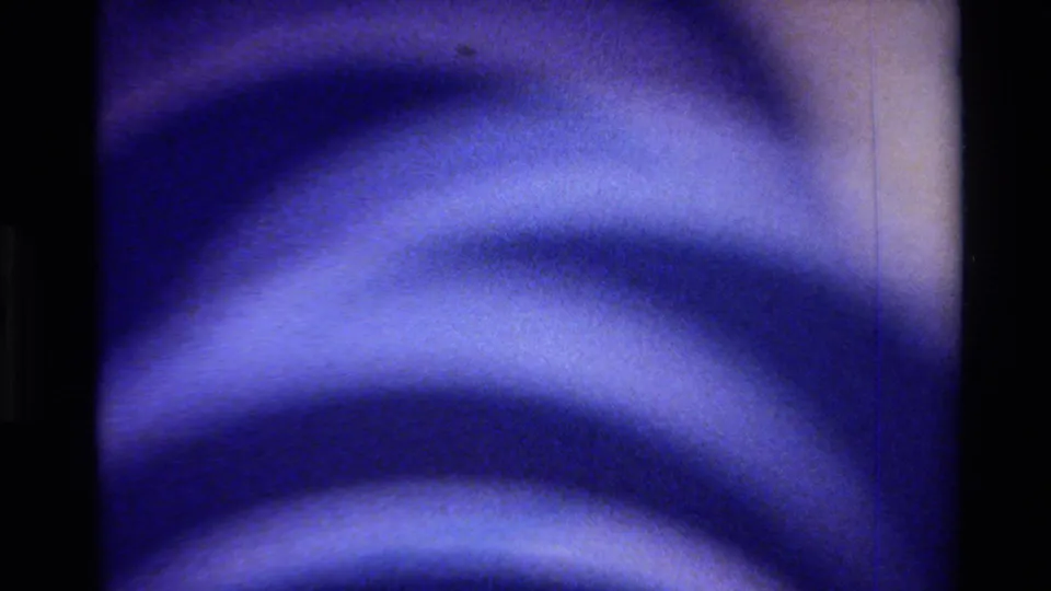 Final abstract 8mm frame from Big Sur metadata, showing saturated blue curved bands, soft highlights, grain, and a pale strip at right.