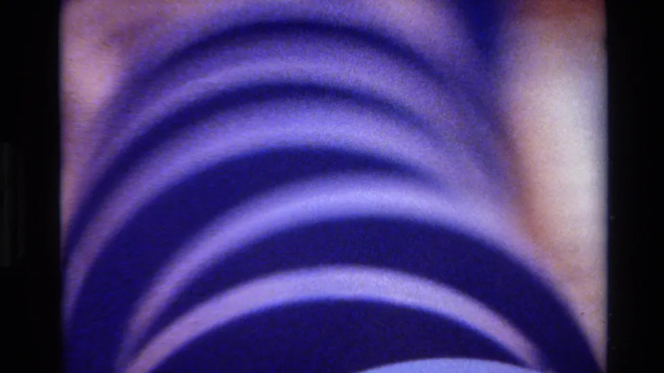 1980 Big Sur 8mm frame with stacked blue-purple concentric bands, soft exposure, and a dark vertical border.