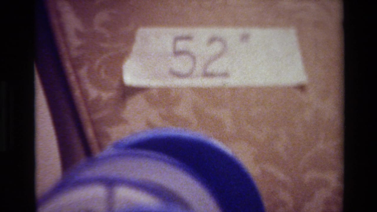 White tape label marked 52 above a blurred blue object on a textured surface.
