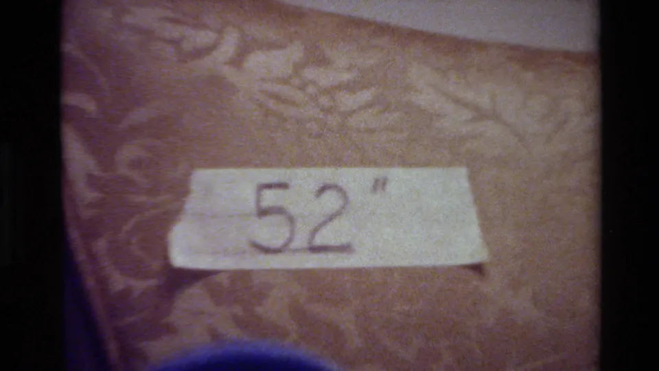 The final frame centers the handwritten 52 on a white tape strip, set against a brown textured surface with soft 8mm grain and a blue foreground edge.