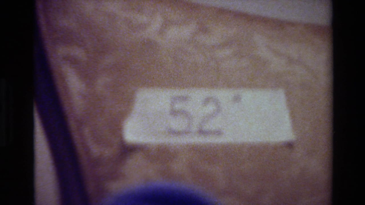 Close 8mm frame of a 52 inch tape label on patterned chair fabric, with the Big Sur 1980 context supplied by clip metadata.