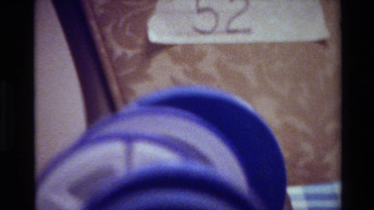 Close-up from 1980 Big Sur home-movie footage showing a blue 8mm reel near a pale label marked 52.