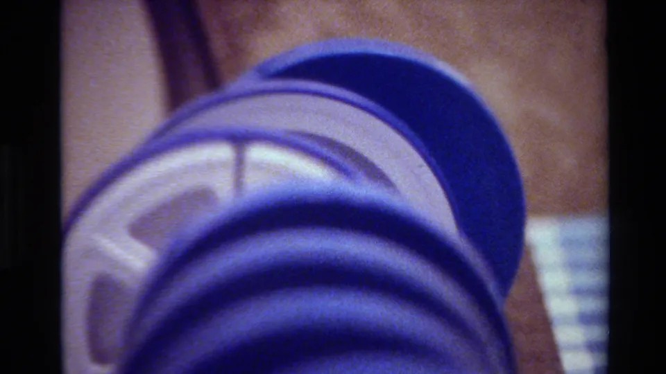 Soft 1980 home-movie close-up of a blue 8mm reel, showing circular ridges and faded film color.