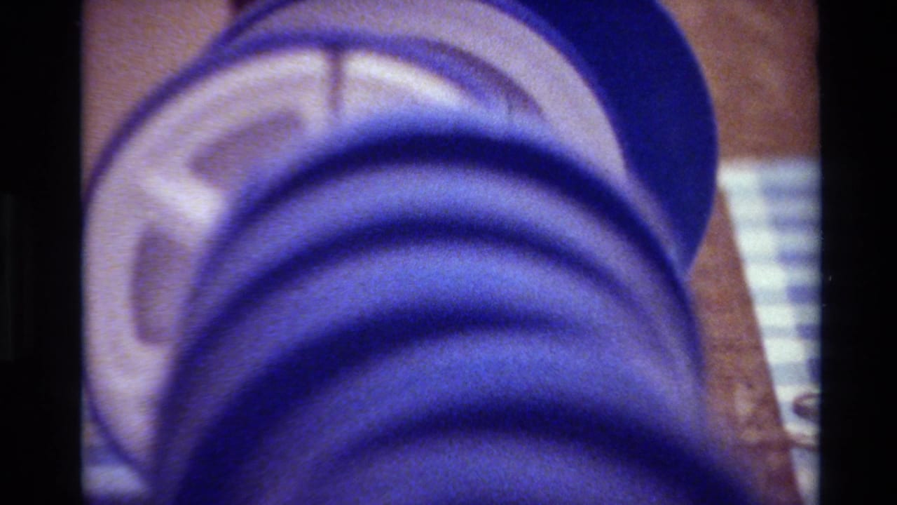 Blue film reel close-up on a wooden surface with checkered cloth behind it.