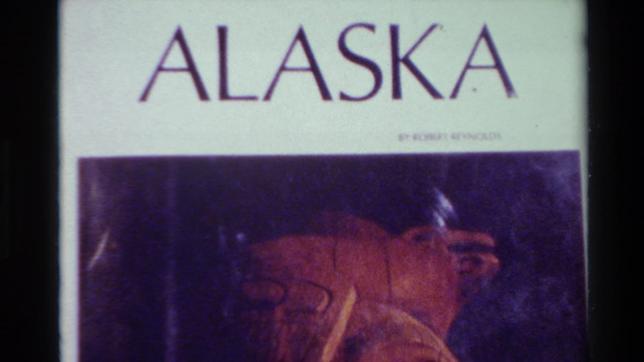 ALASKA title above a reddish carved artifact on a dark background.