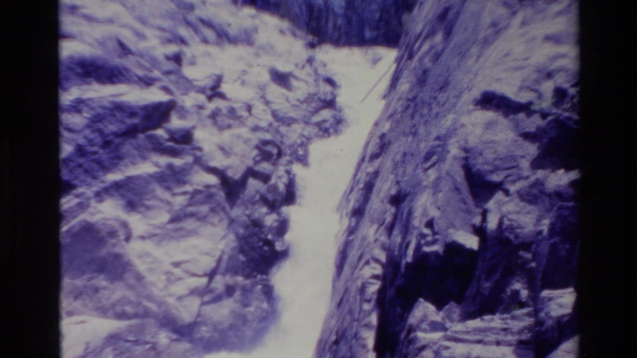 1980 Big Sur 8mm frame showing white water dropping between steep purple-blue rock walls.