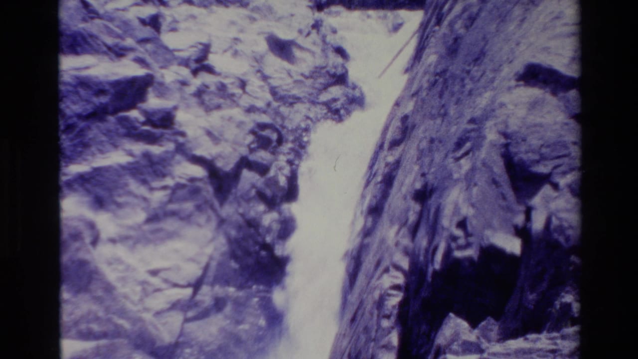 Rocky canyon waterfall seen between dark vertical film-frame borders.