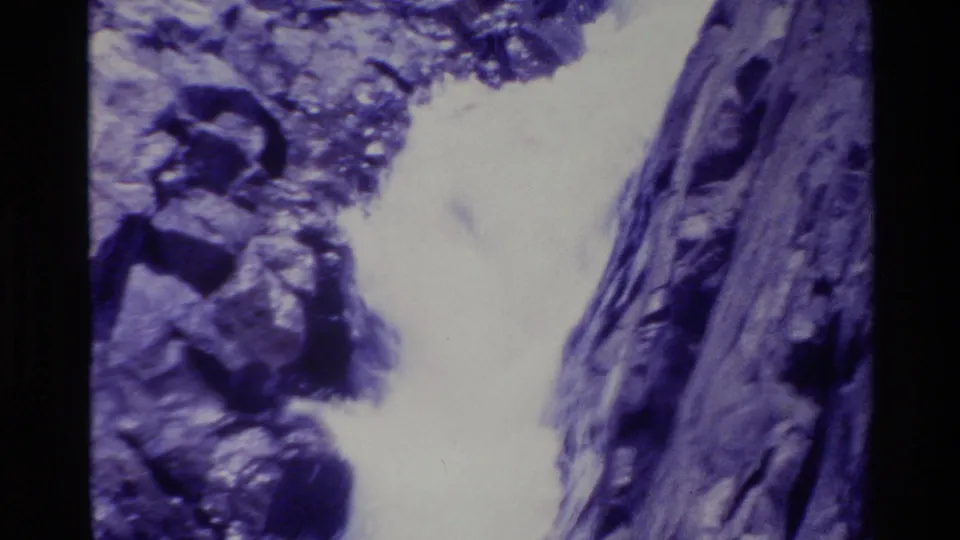 Final Big Sur waterfall frame with white rushing water, steep rocks, and faint vegetation above the canyon.