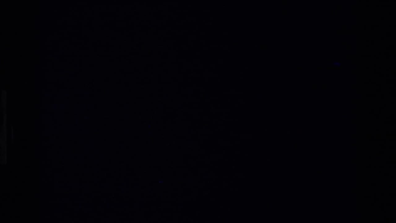 Nearly black film frame with faint grain and little visible detail.