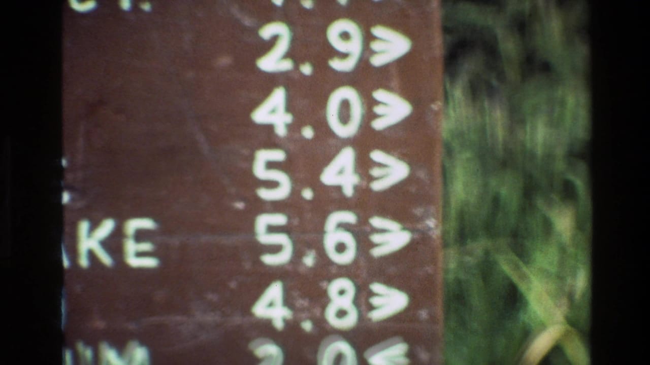 Close crop of the trail sign showing white distance numbers and arrows.