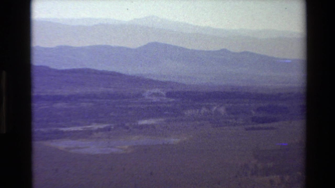 1980 Grand Teton-area home-movie view of hazy mountain ridges receding above a wide valley floor.