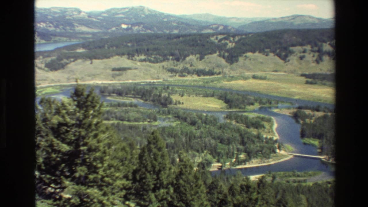 River valley, forest, meadow, low hills, and distant mountains seen through film borders.