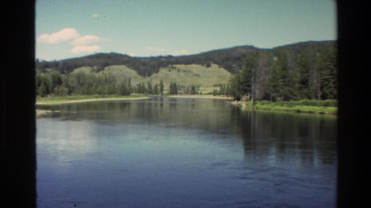 Wide river view with forested banks, hills, and dark vertical frame edges.