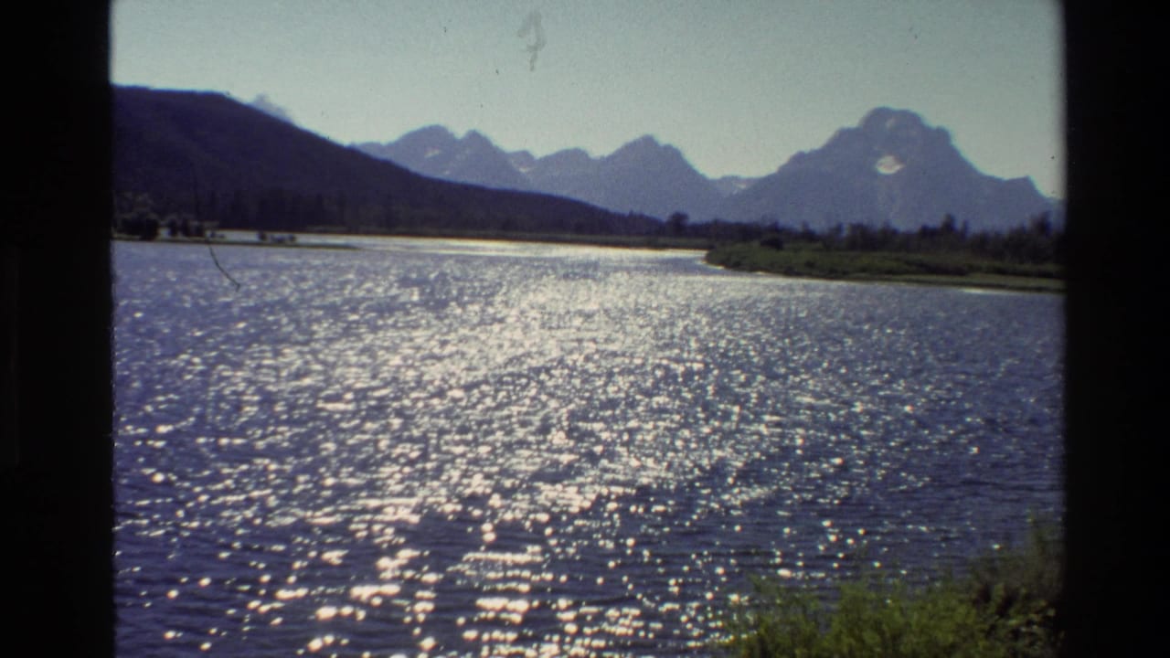 Rippling lake surface with bright sun reflections and mountains across the far shore.