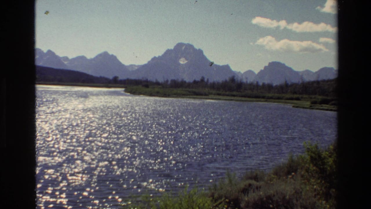 Grand Teton water scene from 1980 home-movie footage, showing sunlit ripples, low vegetation, and distant peaks.