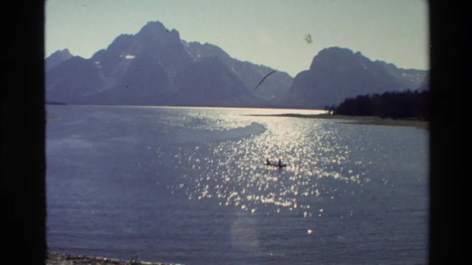 Grand Teton, Wyoming, 1980 8mm frame showing a small boat with distant occupants on bright reflective water.