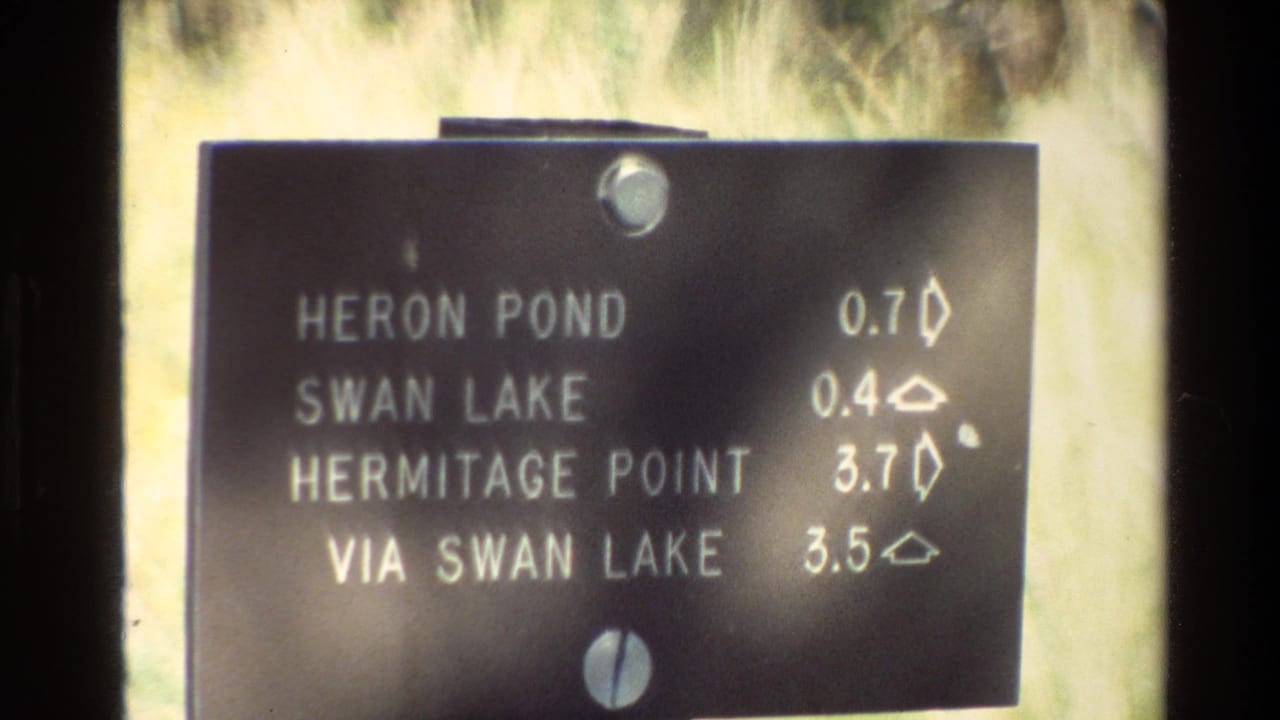 Close view of the same directional sign with trail names and distance markers.