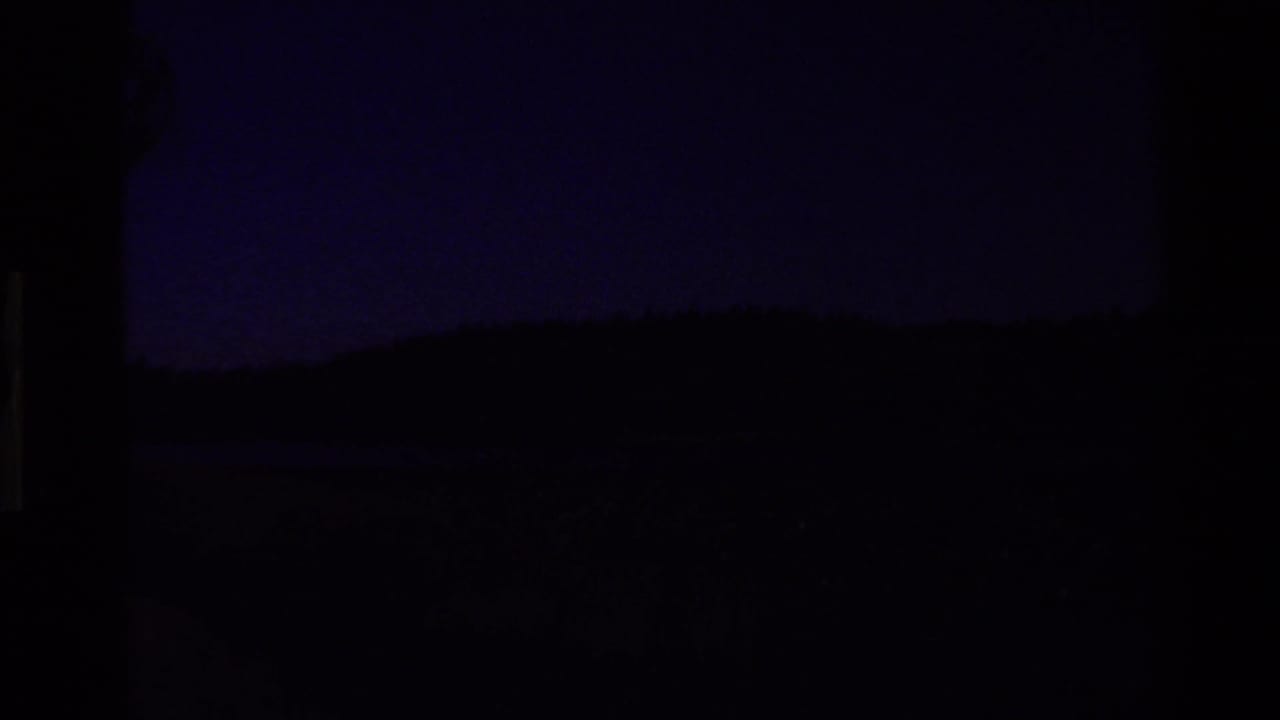 Very dark frame with faint horizon shapes and blue-black exposure.