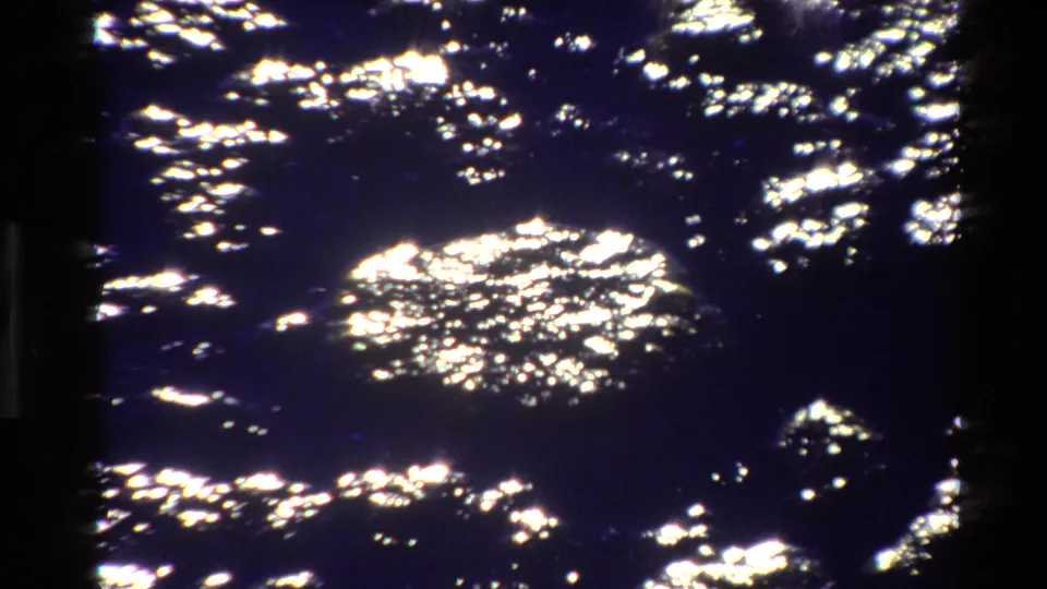 High-contrast water reflections fill the frame, with a dark film edge visible in the 8mm scan.