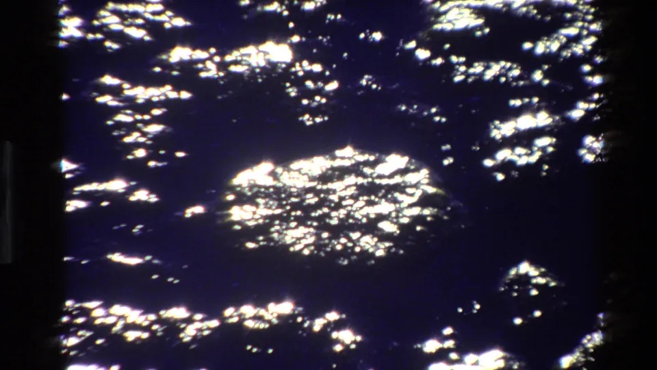 Close view of sparkling lake reflections, retaining the soft grain and contrast of 8mm home-movie footage.