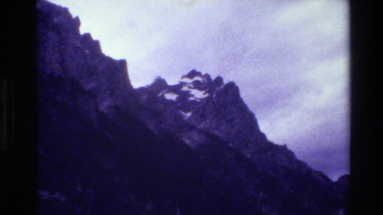 Dark mountain mass and pointed ridge line under a cloudy sky.