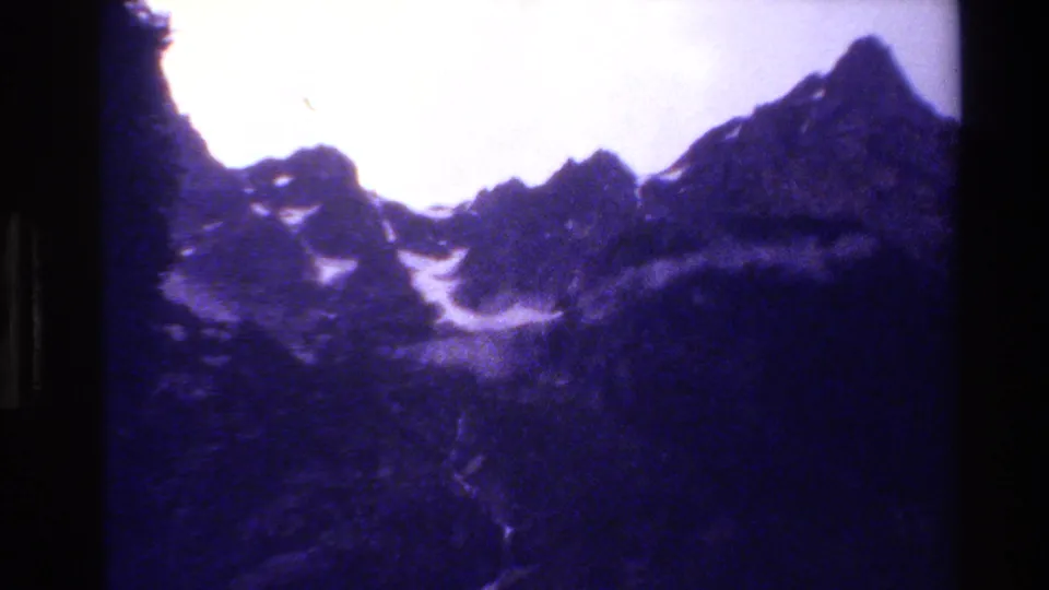 Late-frame Grand Teton landscape showing jagged mountain peaks, snow streaks, and violet 8mm color under a bright sky.