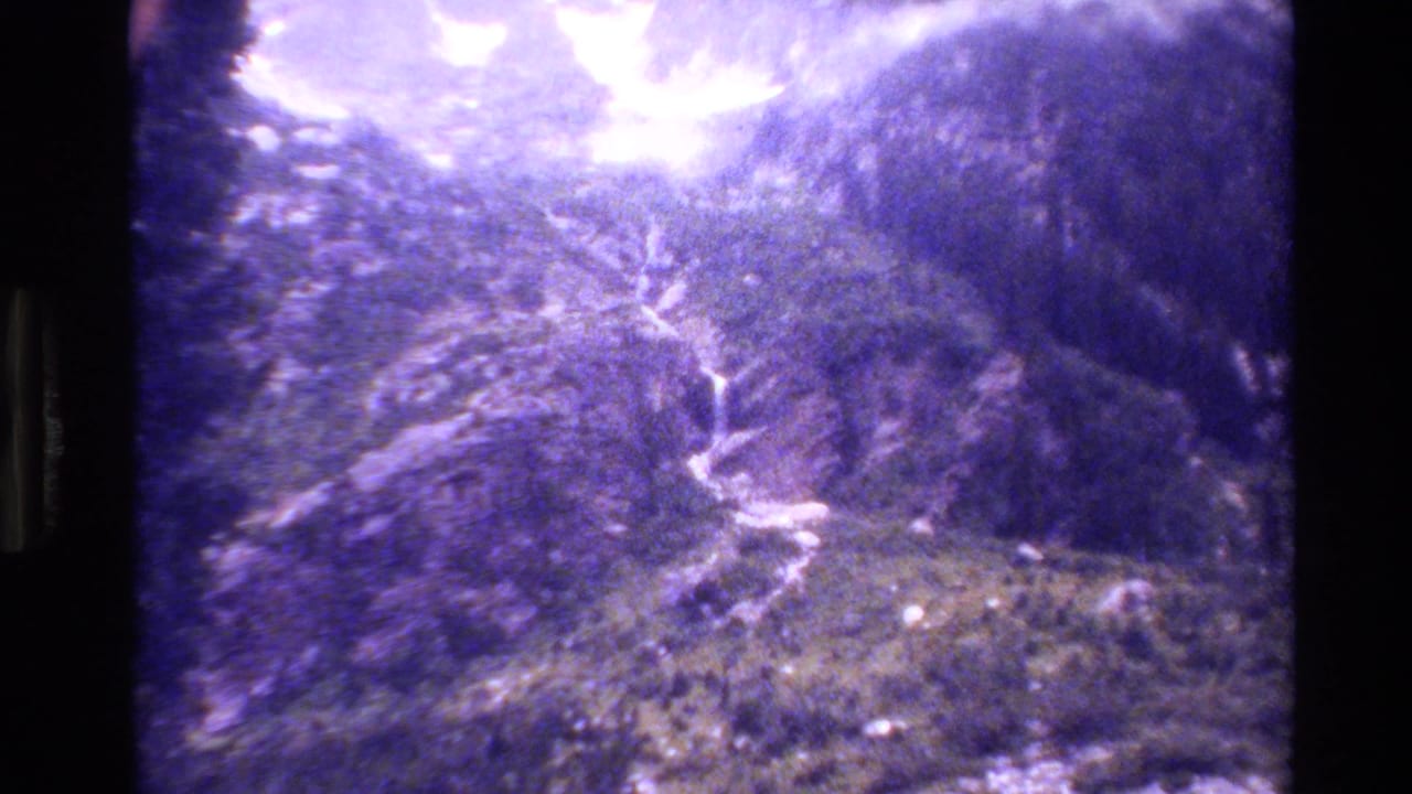 Elevated view of rugged mountain terrain with a pale waterfall or path crossing the slope.