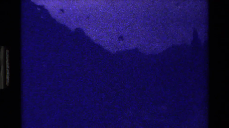 Opening 1980 8mm frame from Grand Teton, Wyoming, showing a dark blue-purple mountain silhouette and film-edge exposure transition.