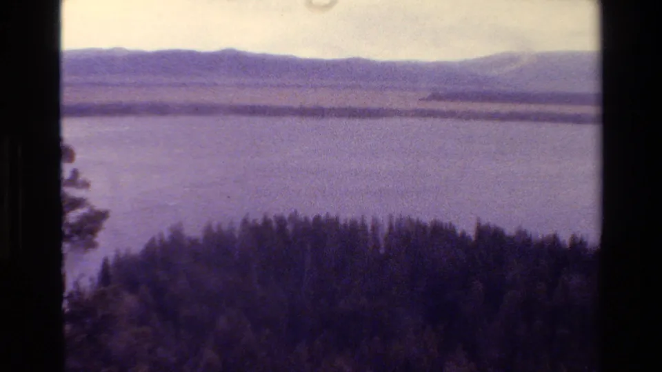 Grand Teton, Wyoming 1980 frame showing a lake below distant mountains, with evergreen forest in the foreground.