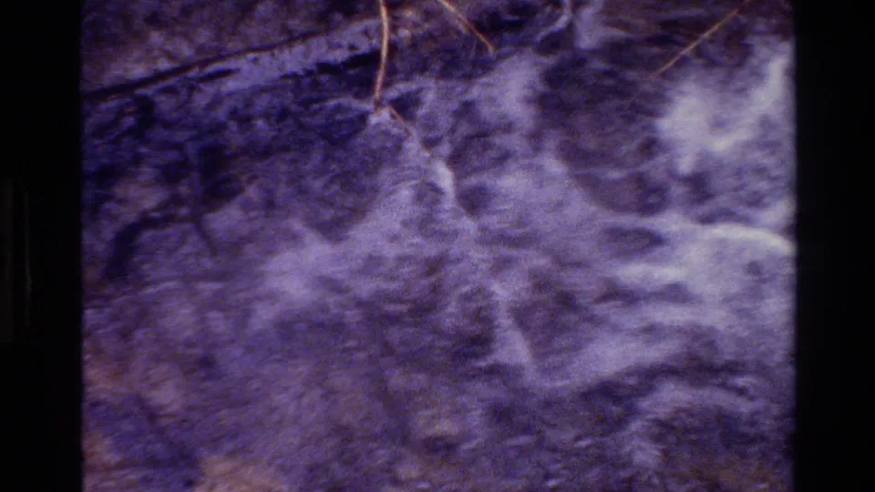 1980 Grand Teton 8mm close-up of rushing stream water passing over rocks, pebbles, and scattered twigs.