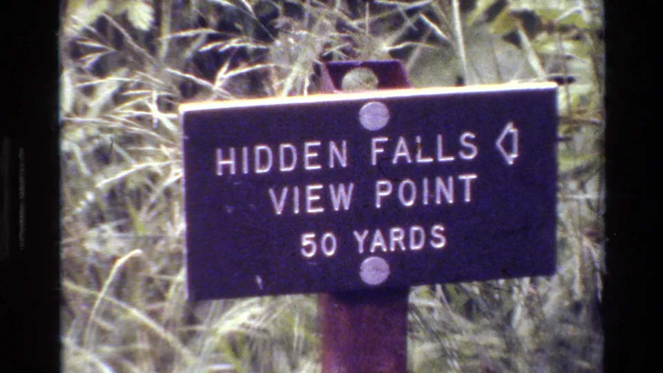 Close visitor-shot view of the Hidden Falls View Point 50 Yards sign surrounded by grass in Grand Teton footage.
