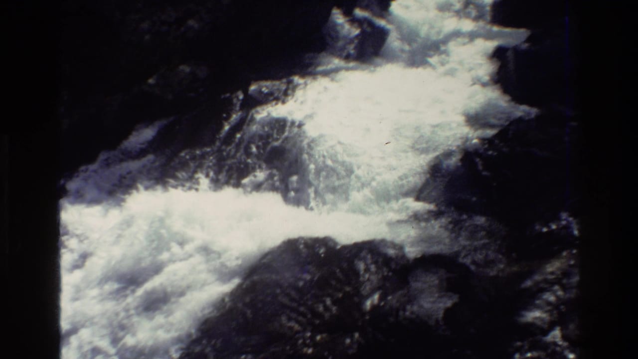 1980 8mm Grand Teton-area footage showing frothy mountain water cascading over dark rocks in a shaded forest setting.