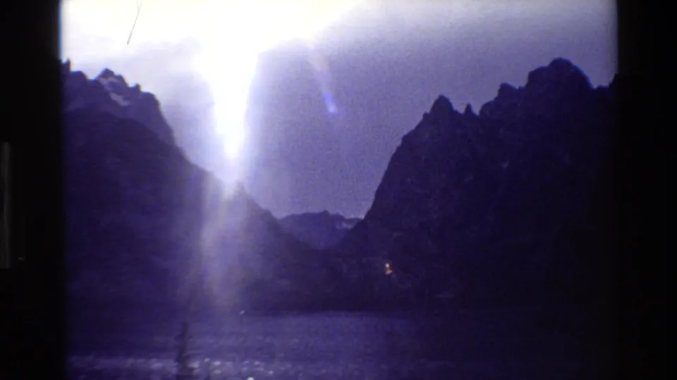 Grand Teton, Wyoming 8mm frame showing a mountain lake, dark ridges, and sunlight piercing through cloud cover.