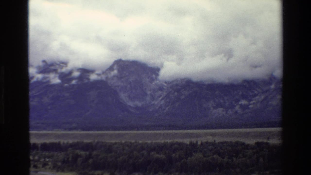Cloud-covered mountains behind a broad forest and valley.