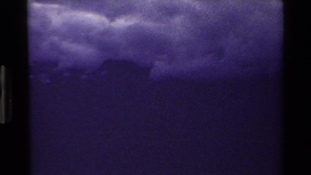 Dark cloudy mountain skyline framed by visible 8mm film edges.