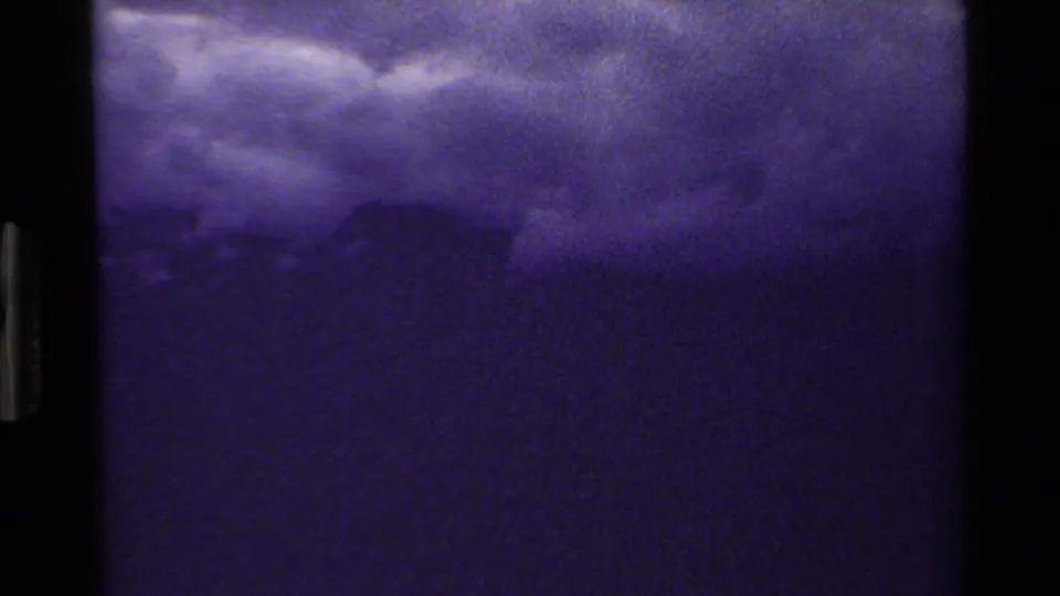 Grand Teton-area 8mm frame with dark mountain silhouettes under heavy clouds and visible film gate borders.