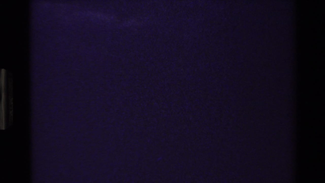 Mostly dark blue-purple frame with film edge artifacts and little visible landscape detail.