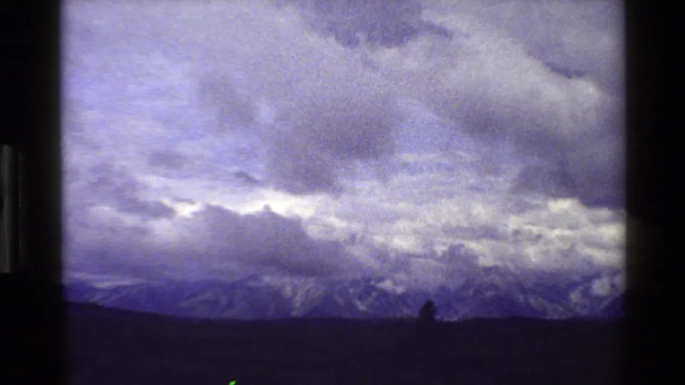 Grand Teton range in Wyoming, 1980, seen through a purple-blue 8mm color shift with clouds over snowy ridges and a dark open foreground.