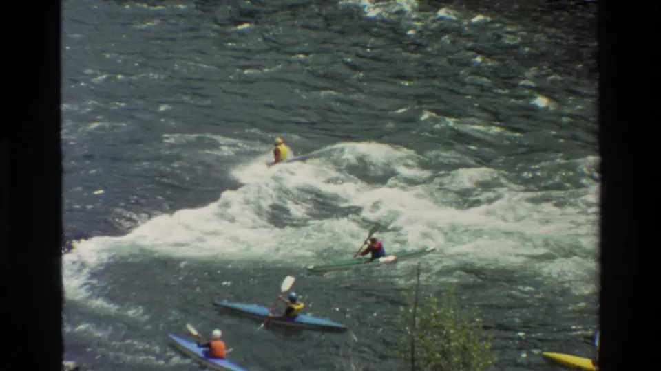 Grand Teton river scene from 1980 with kayakers spaced across turbulent whitewater and dark 8mm frame borders.