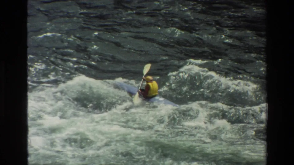 A helmeted kayaker in a yellow vest moves through choppy whitewater in the Grand Teton, Wyoming clip.
